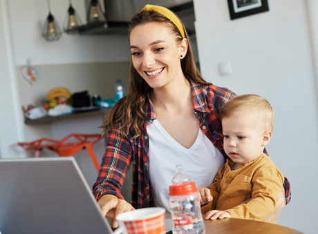 busy mom sitting with her baby in her lap as she happily works
