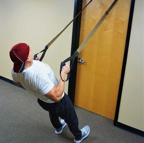 Athlete performing a heavy suspension row with a NOSSK trainer anchored to an office door.