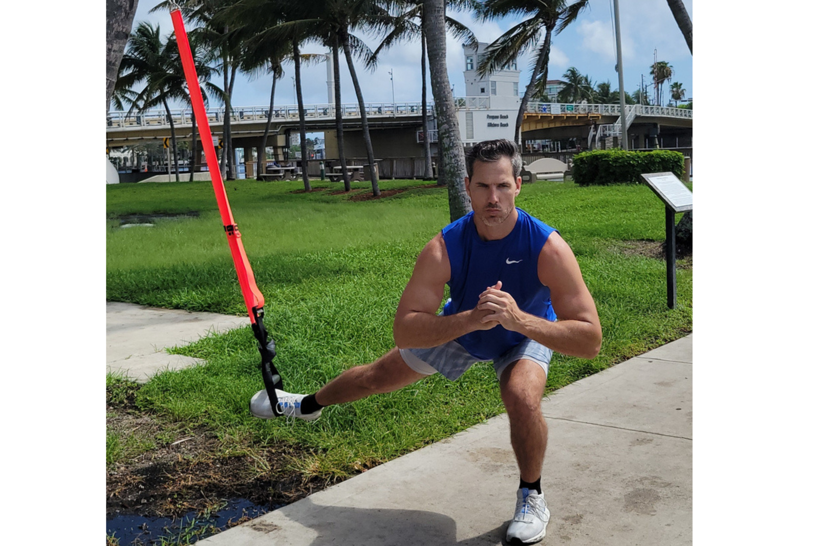 Man exercising with the NOSSK TNT, anchored on a tree trunk outdoorsdoing a side suspended lounge 