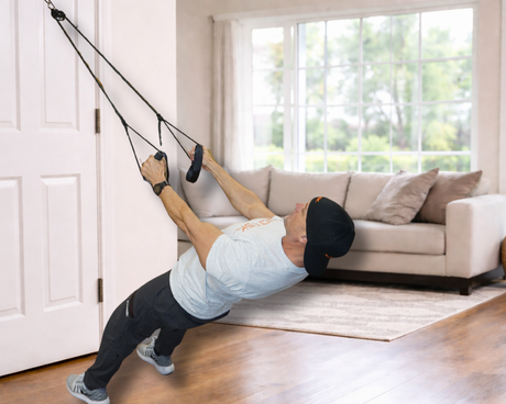 Man working out at home in a bright, well-lit living room with the NOSSK Cyclone Trainer anchored from the door.