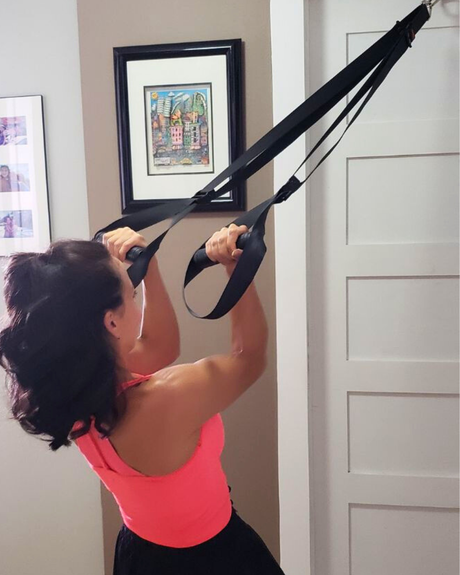 Woman using a premium suspension fitness trainer on a home door to stay consistent with her New Year fitness goals