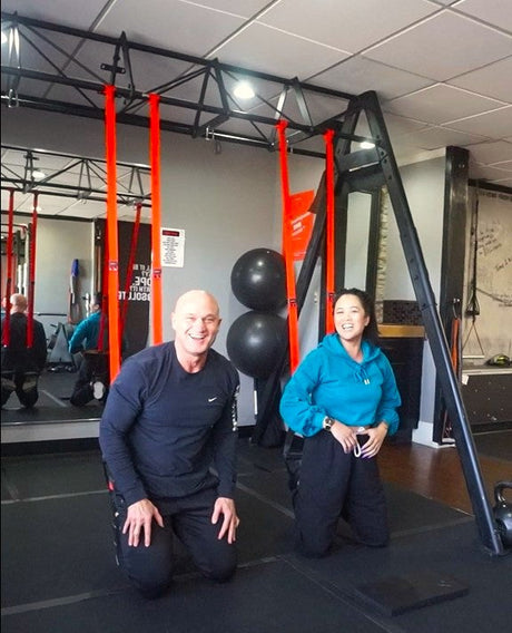 NOSSK athletesTroy and Jemma laughing with satisfied grins after working out together at the gym using the NOSSK GYM Suspension Fitness Trainers anchored from a garage rack
