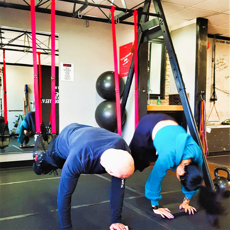 People working out with NOSSK Gym Pro suspension straps in a gym setting